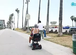 On a public beach sidewalk, a fit MILF granny bends over for doggystyle sex, her tits bouncing wildly.