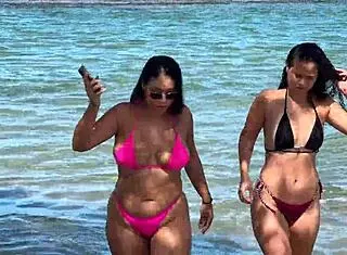 two pretty latinas kiss on public beach first time