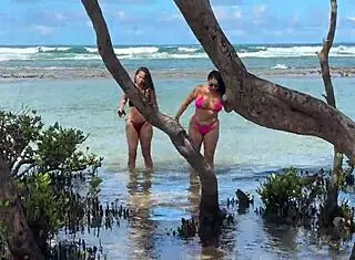 two pretty latinas kiss on public beach first time
