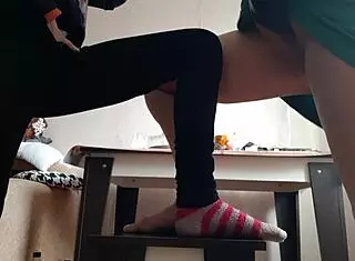 Middle aged woman sits in skirt while student in jeans masturbates nearby