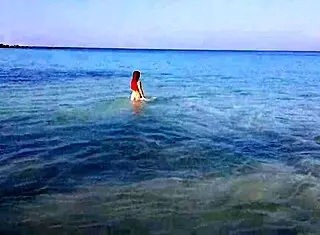 Naked redhead bathes on public beach.