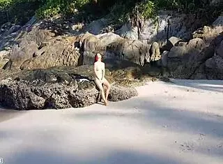 Naked redhead bathes on public beach.