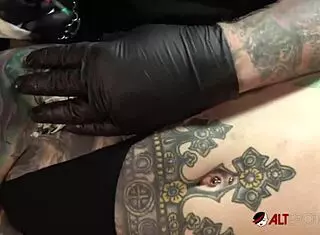 Marie Bossette endures painful tattoo on her leg while exposing pussy and big tits