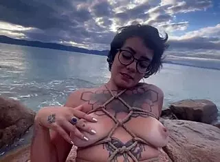 Bold shibari bondage exposes small tits in public outdoor setting