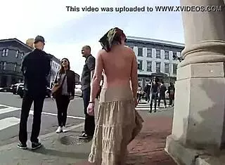 Girlfriend walks topless around town with friend in public outdoor setting.
