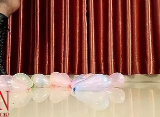 Femdom dominatrix pops small balloons with high heels boots on ass close up