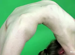 mlada rjavolaska gimnastičarka anna mostik razpre noge v goli predstavi