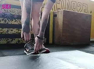 Alternative girl stretches at the gym, showing off her tattoos. 😏